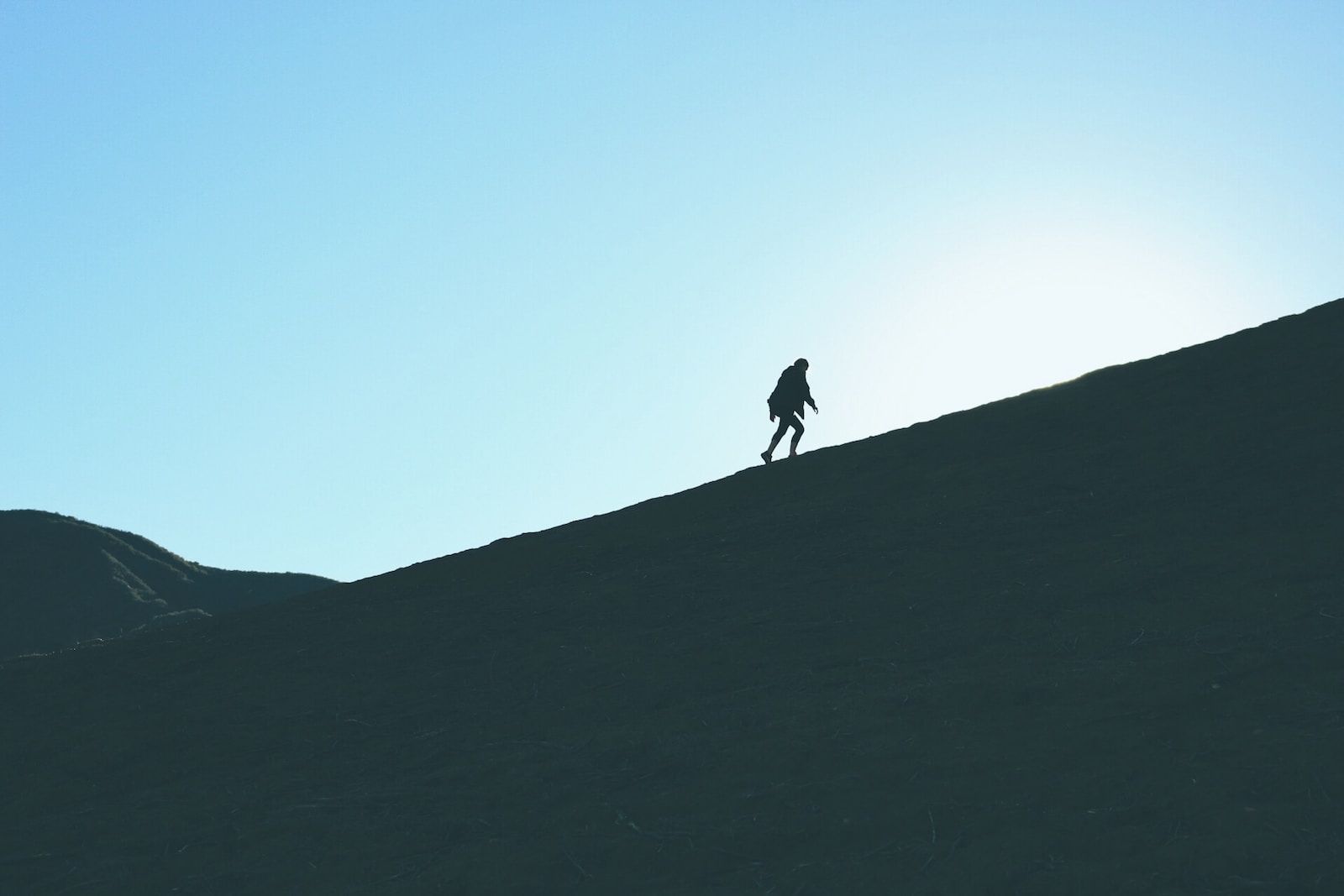 silhouette of man climbing hill