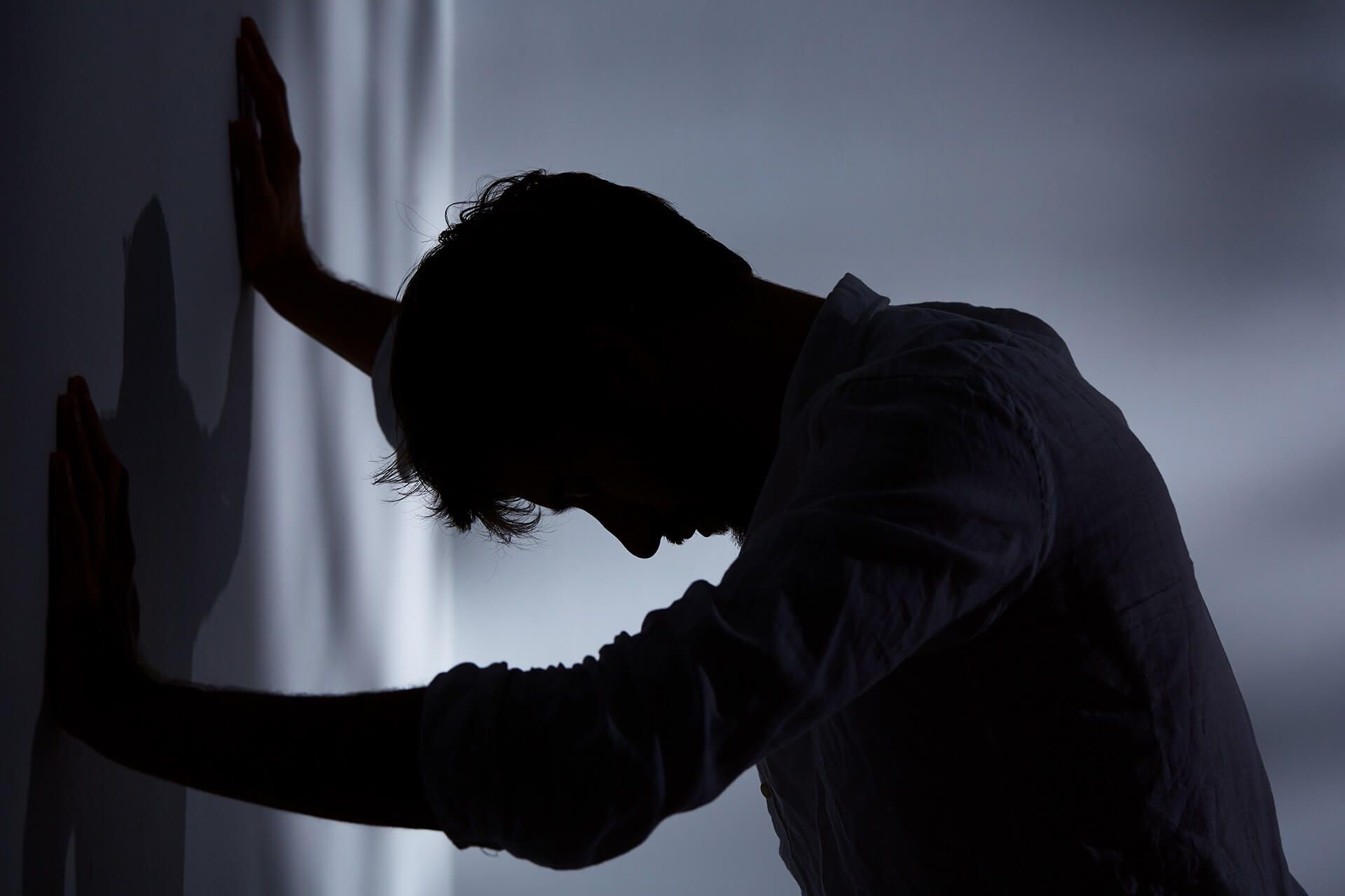 Depressed man leaning against a wall